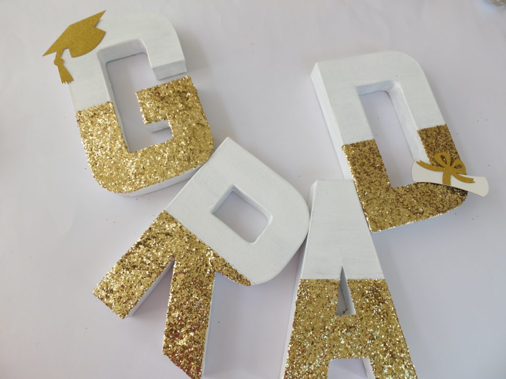 DIY glitter paint paper mache letters cardboard graduation centerpiece, gold glam glamorous grad decor, best open house graduation party ideas, best grad party ideas for girls daughter teenagers teens