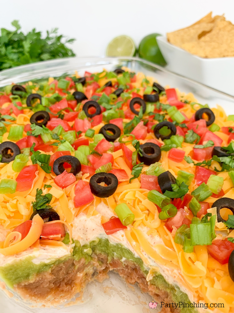 The best layered taco dip, easy best taco dip recipe, hot or cold taco dip recipe, easy appetizer dip for big game superbowl, best picnic potluck ideas for a crowd easy family friendly budget meals, beans guacamole sour cream taco seasoning tomato onion cheese olives lime taco dip