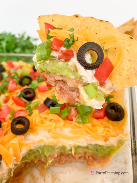 The best layered taco dip, easy best taco dip recipe, hot or cold taco dip recipe, easy appetizer dip for big game superbowl, best picnic potluck ideas for a crowd easy family friendly budget meals, beans guacamole sour cream taco seasoning tomato onion cheese olives lime taco dip