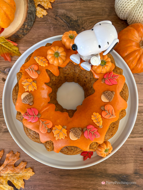best easy Snoopy Pumpkin Spice Bundt Cake recie, Duncan Hines Snoopy The Great Pumpkin Bundt Cake and Glaze Mix, easy best fall cake, easy best pumpkin spice cake for fall, sweater weather Snoopy, Snoopy with a sweater, how to make Snoopy sweater with mini pumpkins and latte, fall decorated bundt cake with icing leaves and Trader Joe's chocolate pumpkins